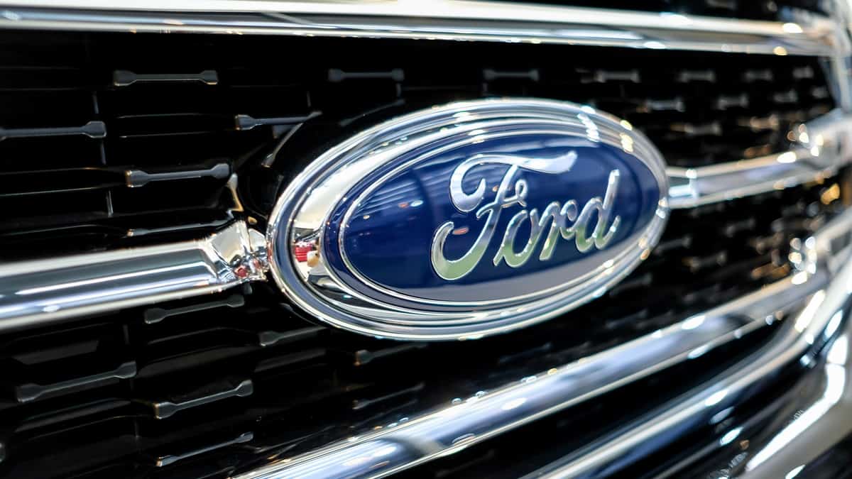Ford logo in front of front grill of pick up and light truck. American automobile manufacturer that designs, engineers, produces, markets and distributes vehicles