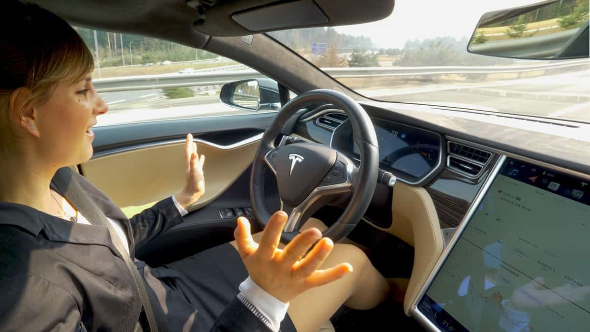 Young businesswoman is surprised at her autonomous Tesla car driving her to work