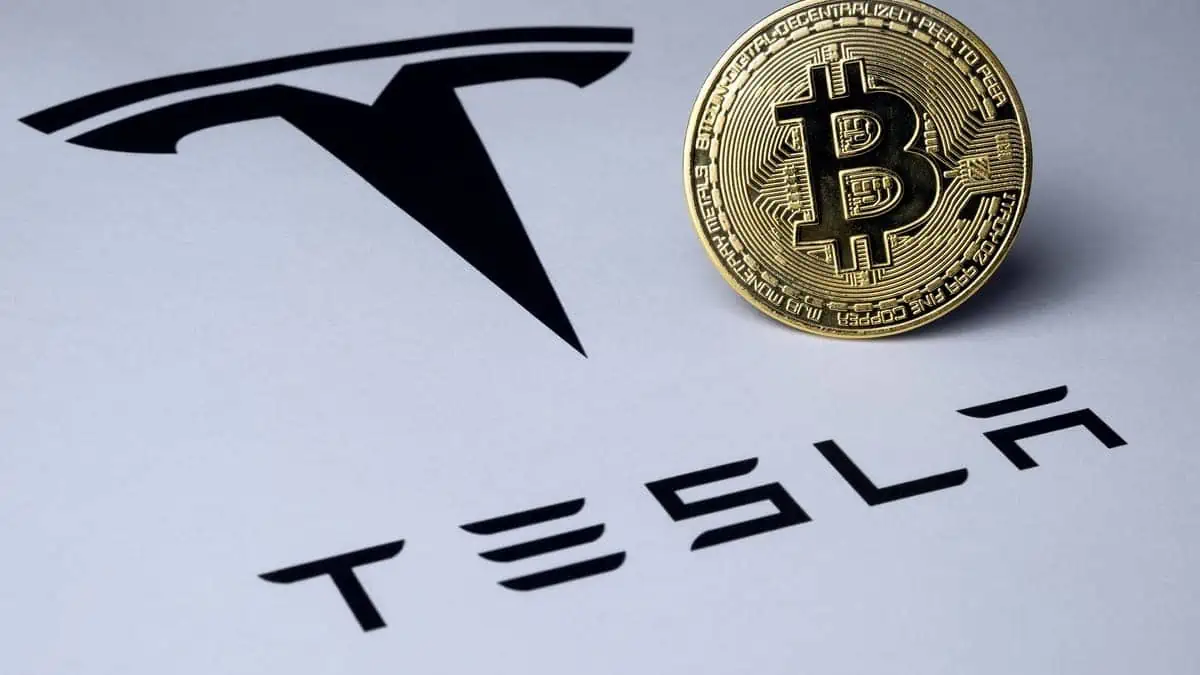 Bitcoin and Tesla logo seen on paper document.