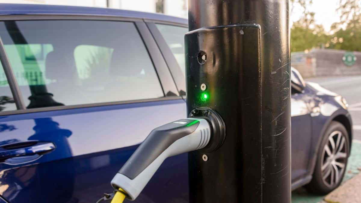 Electric car being charged from a charging point on a street light post