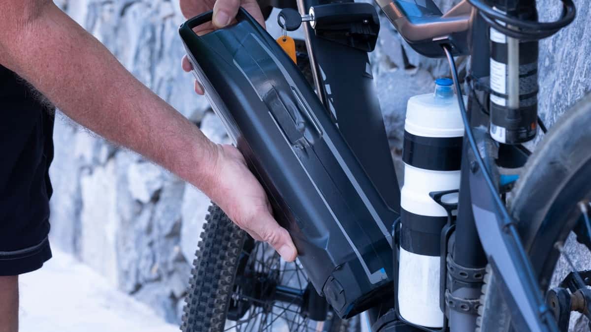 Hands of a man inserting the battery to the electric bike. Healthy lifestyle