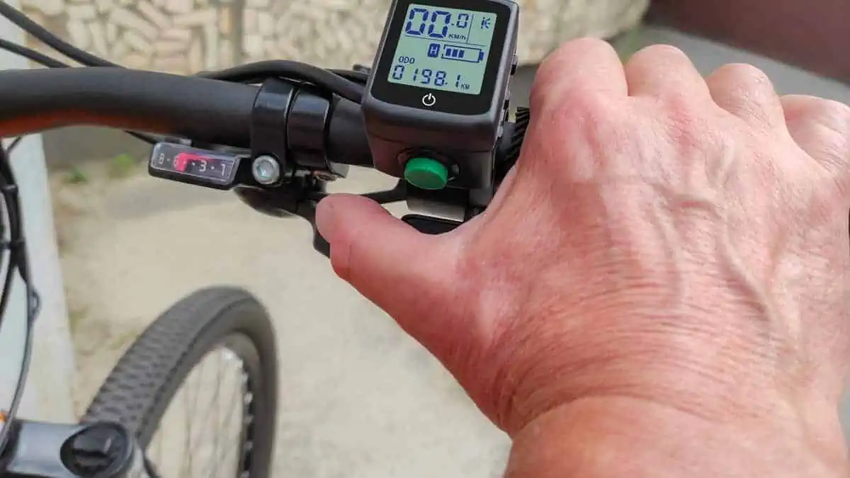Male hand on trigger electronic accelerator of electric bike. Electric accelerator trigger and LCD display with speedometer, odometer, battery charge-discharge controller and other e-bike parameters